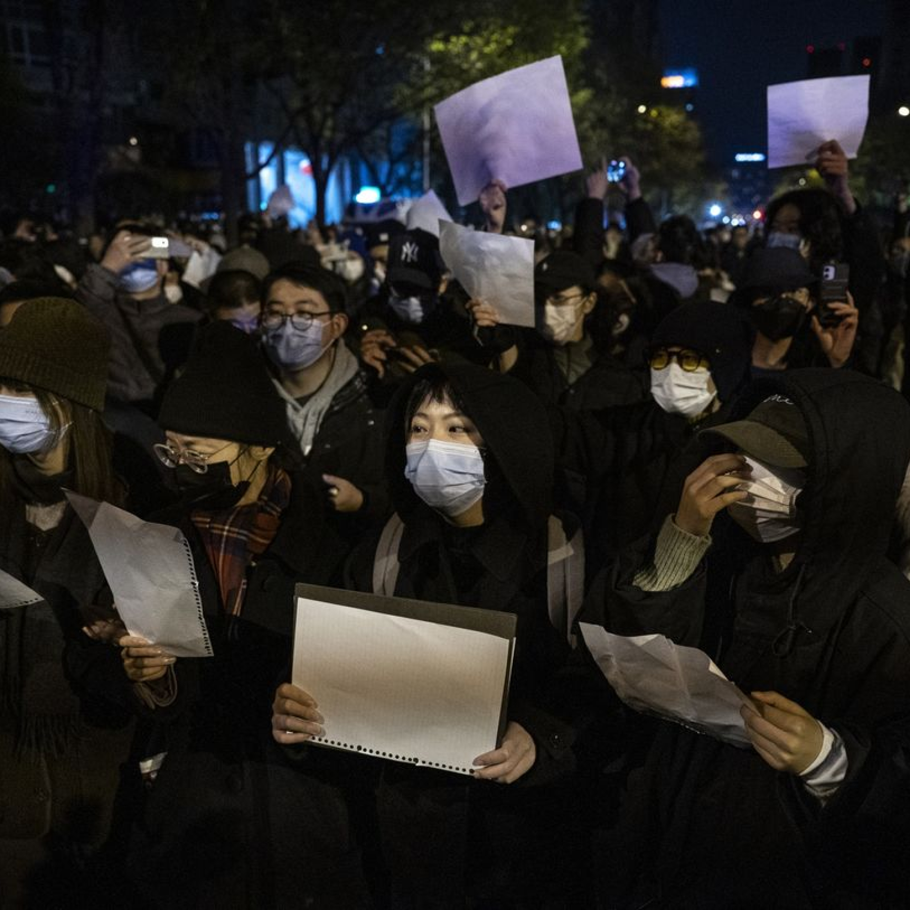 Demonstrators in Beijing hold blank pieces of paper