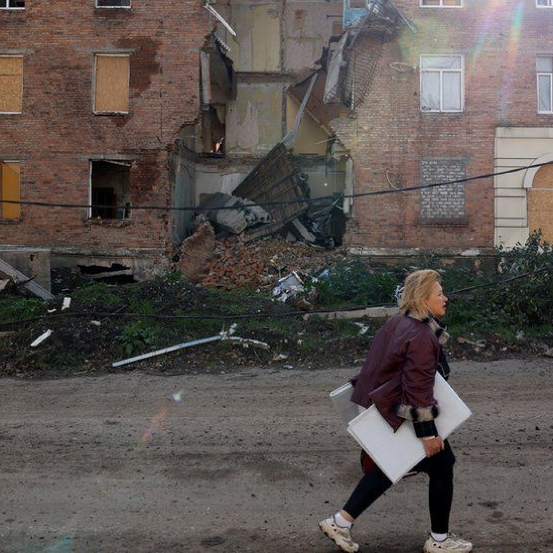 A woman walks past a building damaged by missile strikes in the eastern Donbas region of Bakhmut